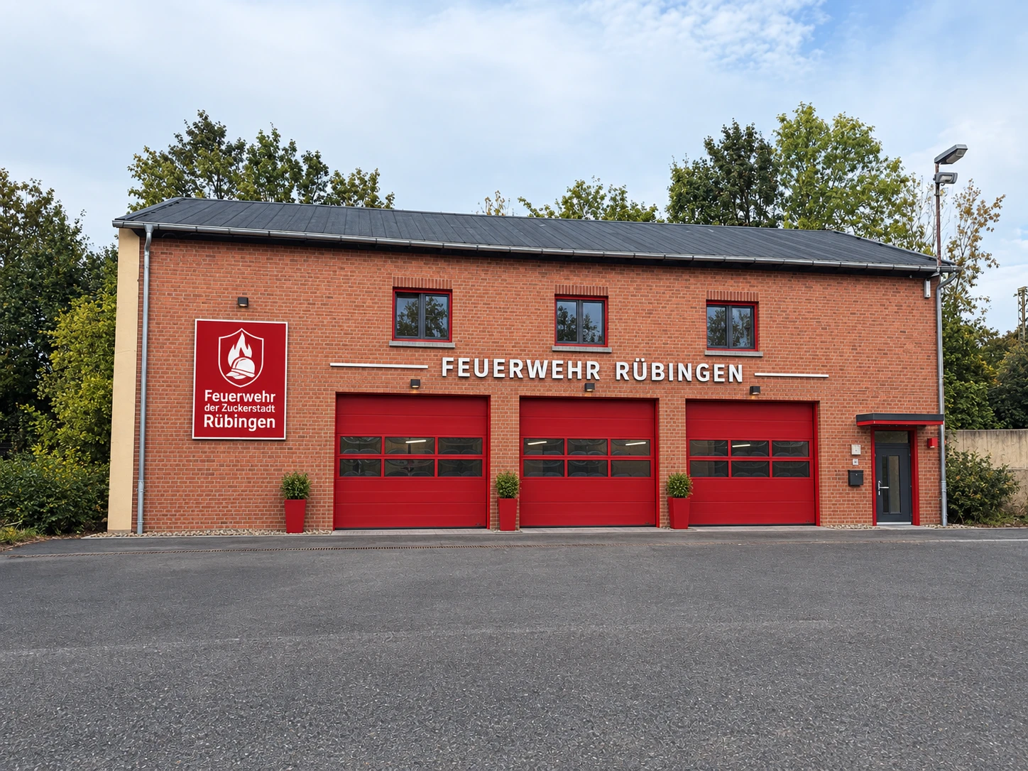 Gerätehaus der Feuerwehr Rübingen: Backsteinbau mit drei roten Toren, dem Schriftzug „Feuerwehr Rübingen“ und dem Wappenschild der Feuerwehr der Zuckerstadt